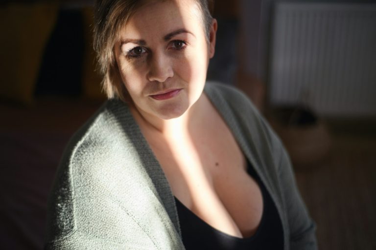 Ritratto di una donna obesa con maglione verde, in luce morbida, con uno sguardo pensieroso.