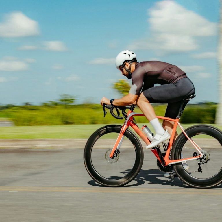 Ciclista in movimento su una strada, indossando un casco e abbigliamento sportivo.