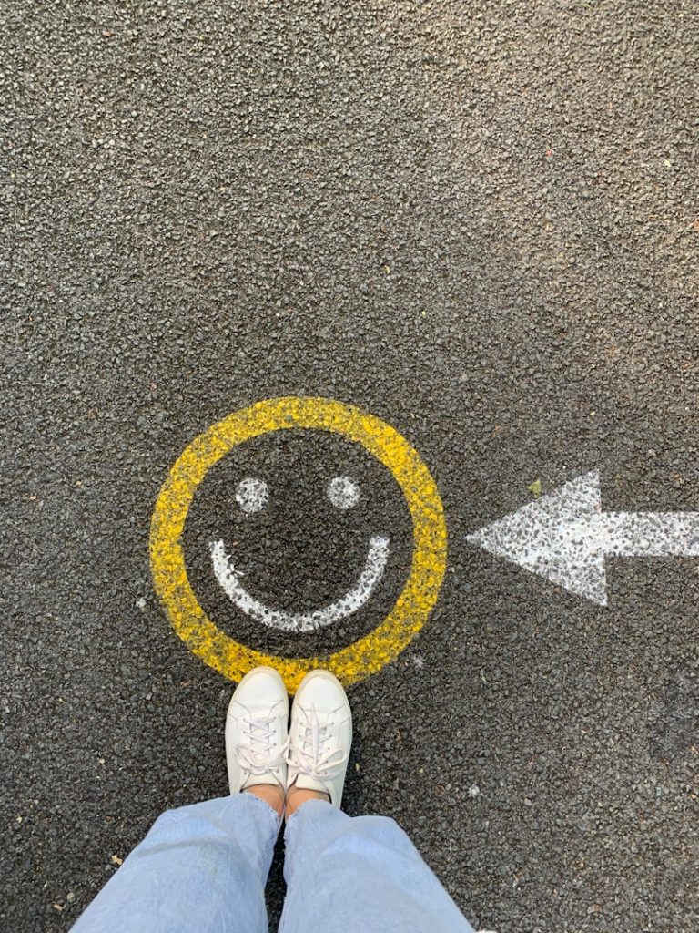 A person's feet near a yellow smiley face with an arrow pointing right.