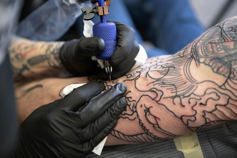 Tattoo artist working on intricate designs on a person's arm.